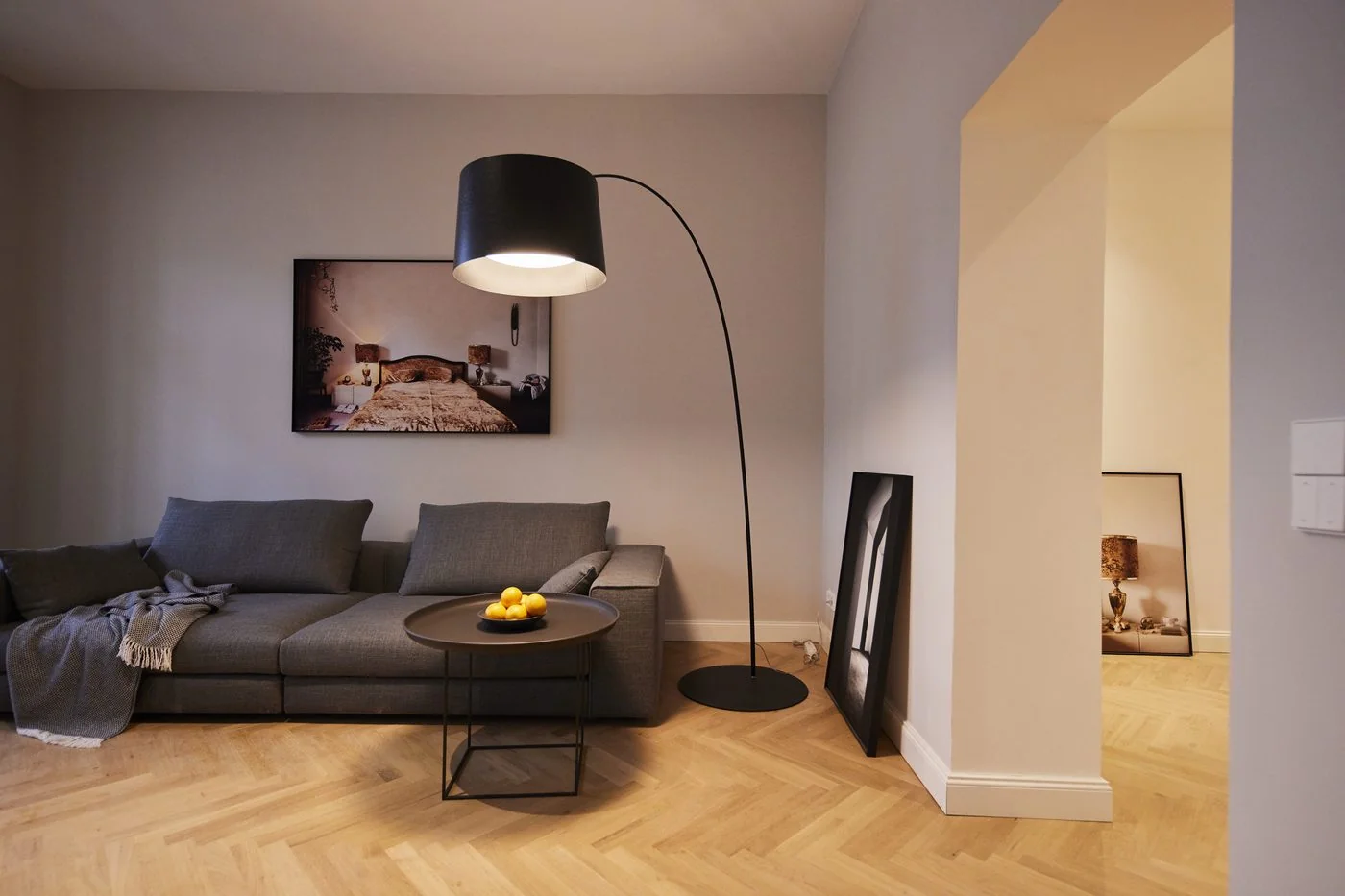 Wohnbereich einer Altbauwohnung im Ostbek 6 mit Designsofa, Bogenleuchte und Fischgrät-Parkett