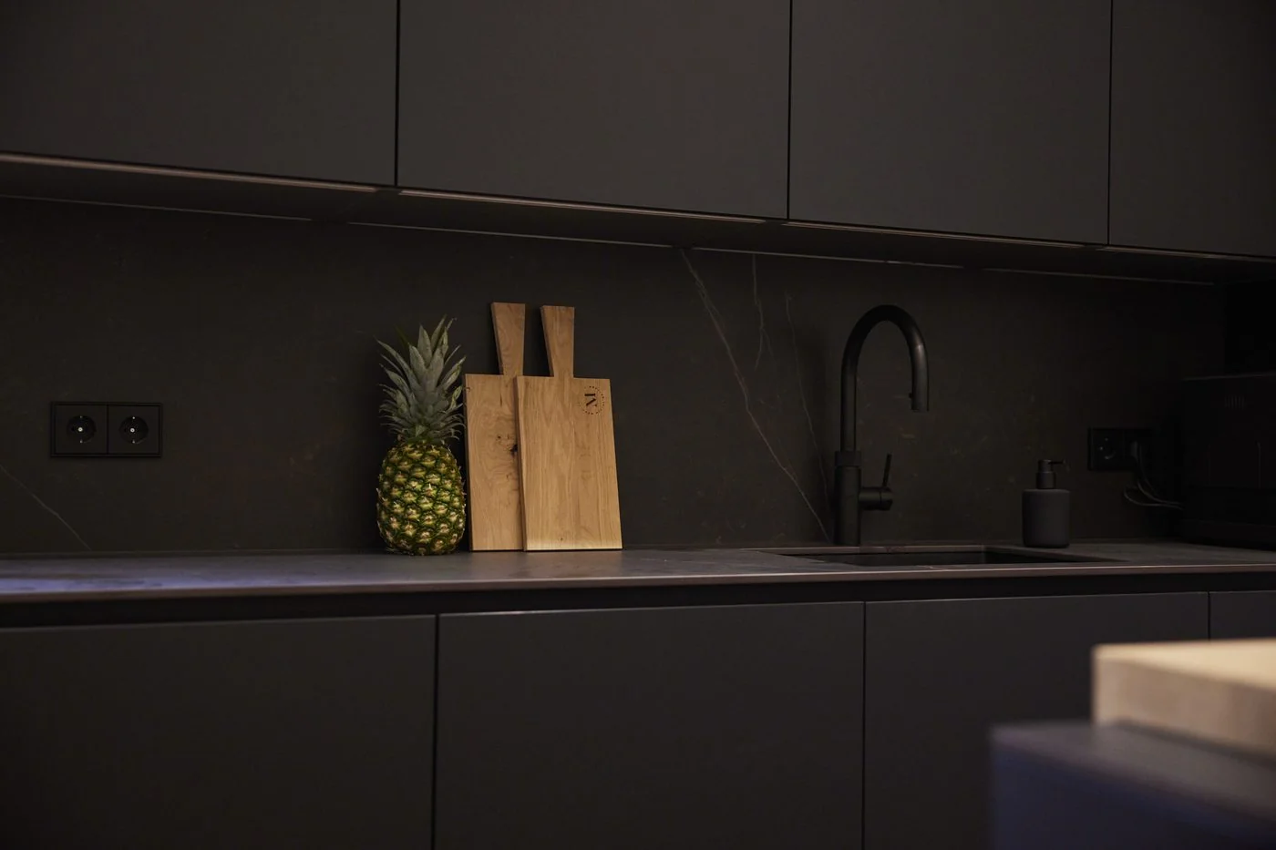 Detailaufnahme der schwarz-matten Designerküche im Ostbek 6 mit Naturstein-Arbeitsplatte